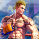 A blonde, tattooed fighter stands ready for battle in the middle of a boxing ring.